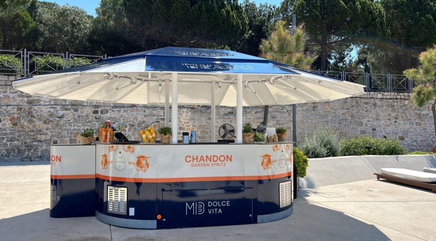Mobilni bar pod suncobranom uz kameni zid